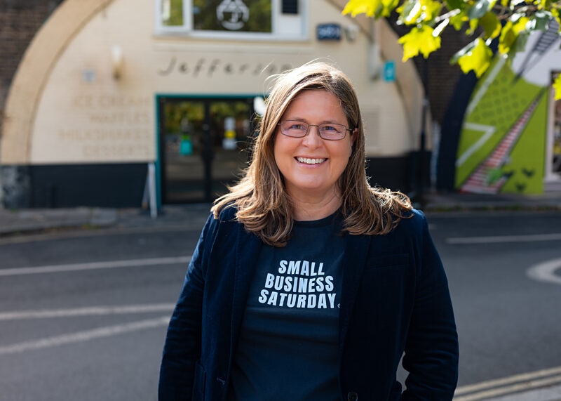 Michelle Ovens CBE, Director of Small Business Saturday UK, smiling in a Small Business Saturday t-shirt outside Jefferson's Ice Cream in Brixton